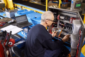 Technician testing electrical control panel during equipment maintenance